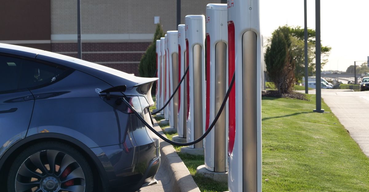 Electric car plugged into a row of charging stations, showcasing modern EV infrastructure.
